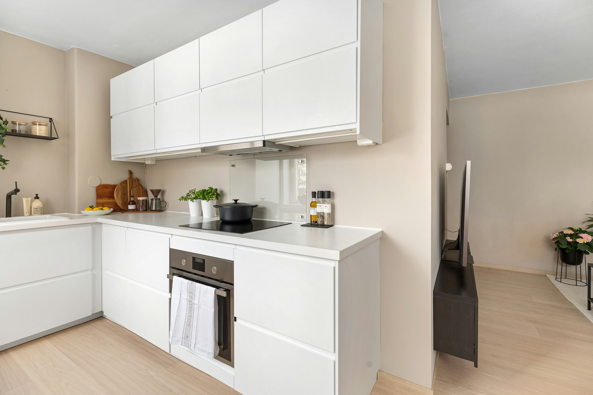 A kitchen with white cabinets and wooden floors
